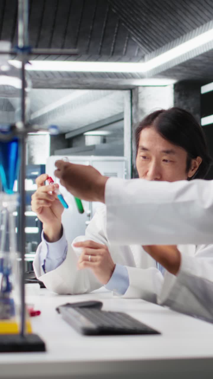 Vertical video Multiracial lab engineers inspect liquids in test tube
