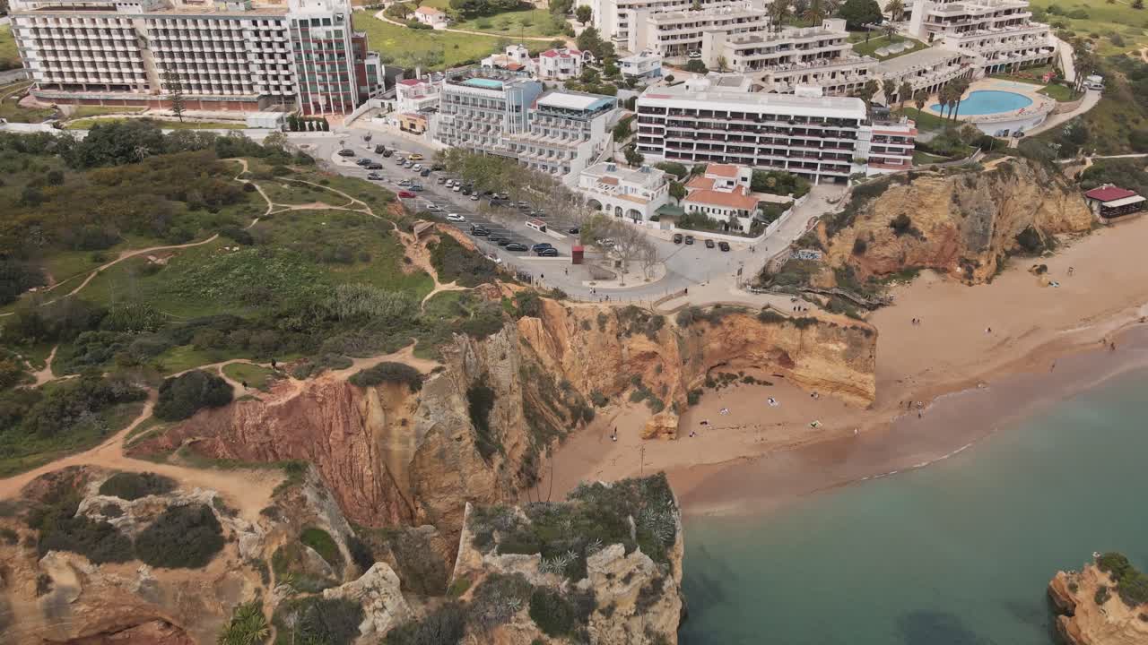 Luftdrone flyver hen over klipper og turkisblåt vand og ender med panoramaudsigt over Lagos by i Algarve.