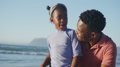 Feliz-Padre-Afroamericano-Hablando-Con-Su-Hija-En-La-Playa-Soleada