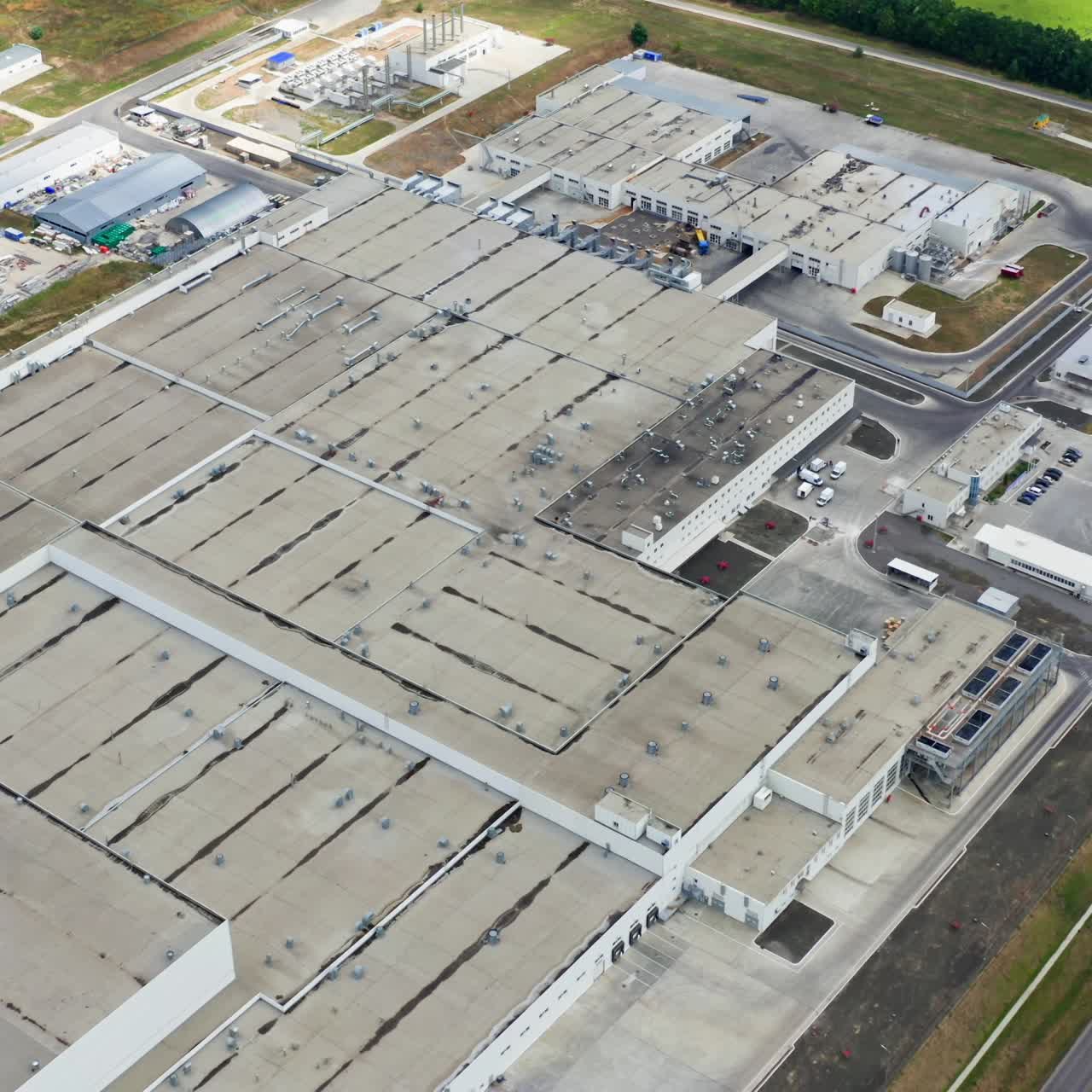 Industrial complex. View from above on roofs of buildings of manufacture. Large factory on green field
