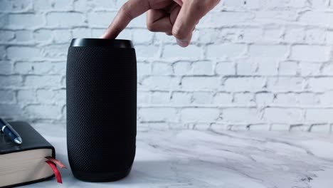 hand touching a black portable bluetooth speaker