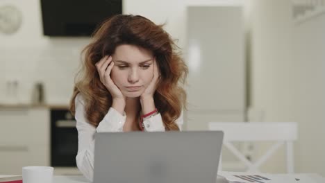 serious woman working computer at remote workplace. puzzled girl looking notebook