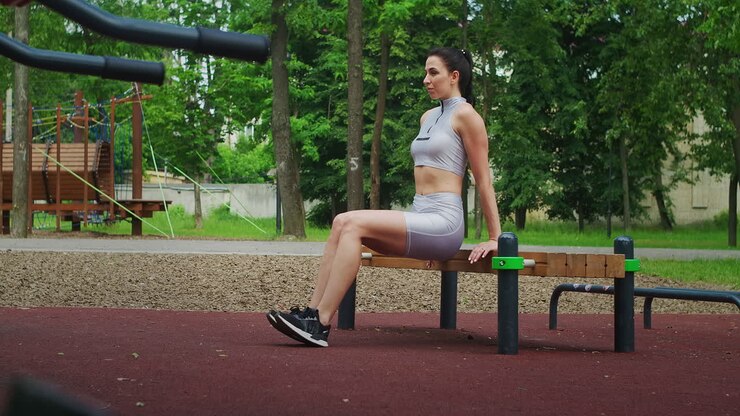 Fit woman do reverse push ups using bench in a Park in slow motion. Beautiful woman playing sports in the Park.