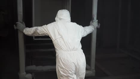 industrial worker painting metal parts in a paint booth