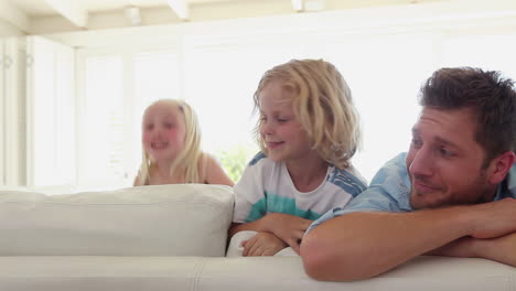 family appearing from behind a couch one after another