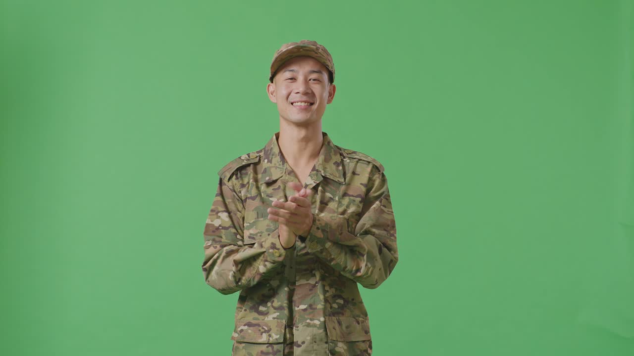 Asian Man Soldier Smiling And Clapping His Hands While Standing In The Green Screen Background Studio
