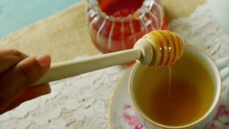 hand pouring honey in herbal tea 4k