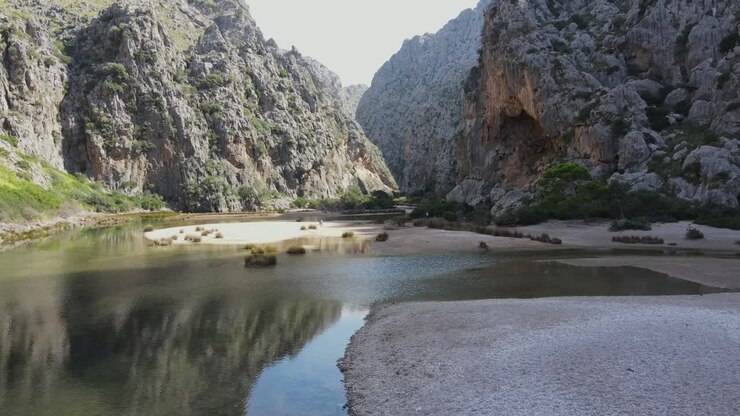 Scenic drone view of a valley at sa calobra Mallorca with water running beneath and mountains towering on the sides