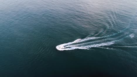 drone view of boat sailing to the left on open ocean on a warm sunny summer day in the faroe islands