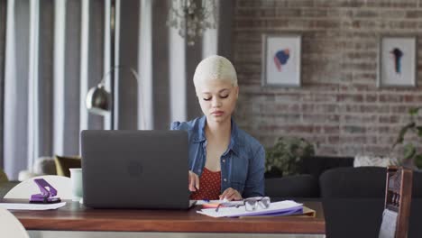 busy biracial woman working at home with laptop in slow motion