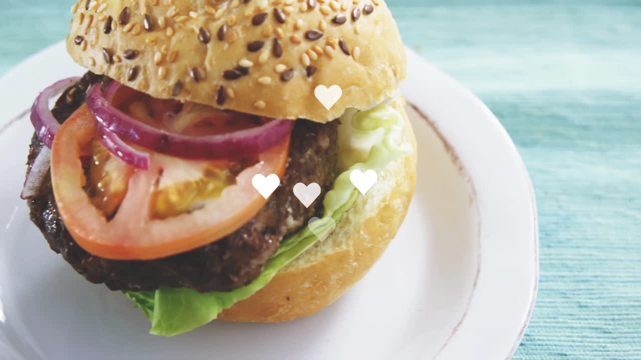 Hearts animation over close-up of delicious burger on white plate