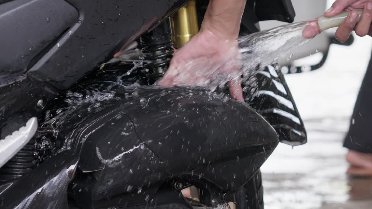 Water splashing as a scooter is rinsed with a hose