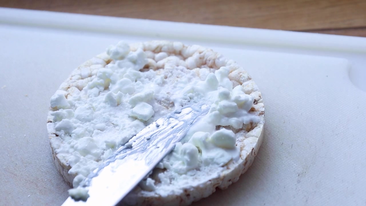 Video che mostra come spalmare ricotta su un cracker di riso