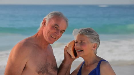 una pareja de ancianos escuchando una concha marina