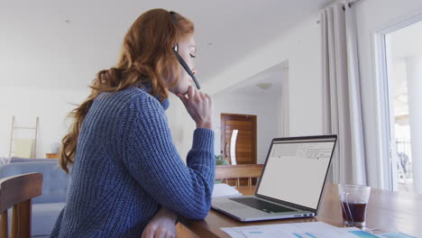 mujer caucásica sentada en un escritorio viendo el procesamiento de datos de codificación en la pantalla de una computadora portátil