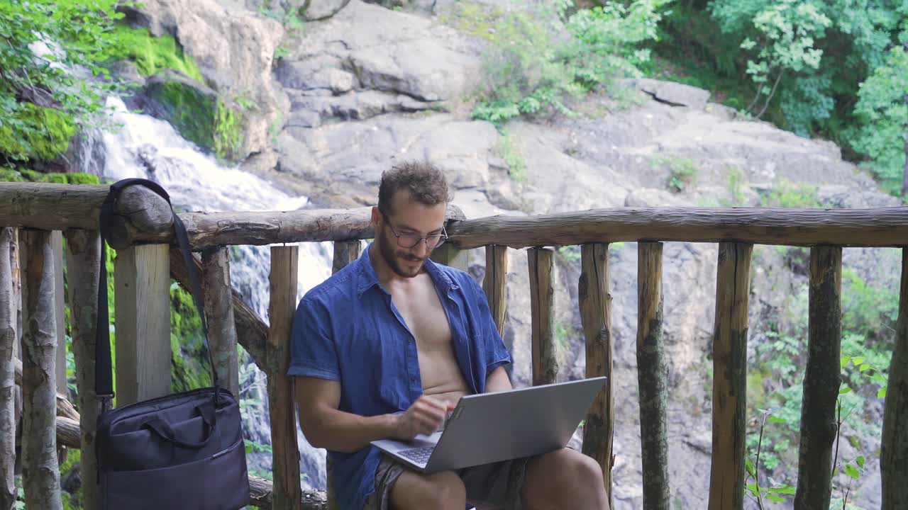 hombre de negocios casual trabajando con una computadora portátil en la cascada.