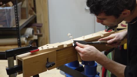 Fabricante-De-Guitarras-Trabajando-Con-Cincel-Cortando-Facetas-En-La-Parte-Posterior-Del-Cuello-De-La-Guitarra-En-El-Taller