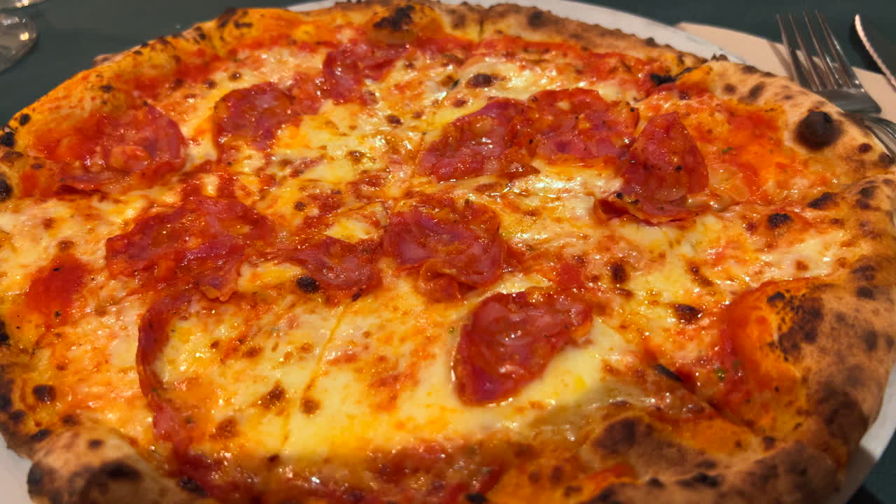 Pizza tradizionale italiana piccante al salame, crosta perfetta, vera pizza napoletana autentica, cibo gustoso, ripresa in 4K