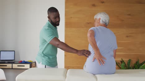 Video-of-african-american-male-physiotherapist-examining-caucasian-senior-woman