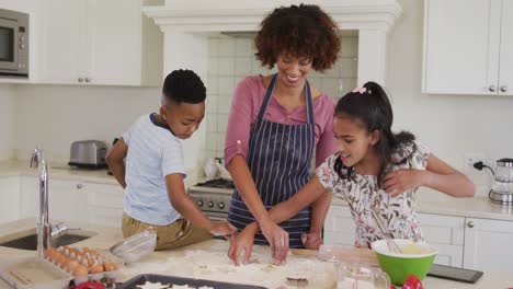 African-american-mother,-daughter-and-son-in-kitchen-cooking,-looking-at-tablet