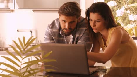 couple using laptop in the kitchen