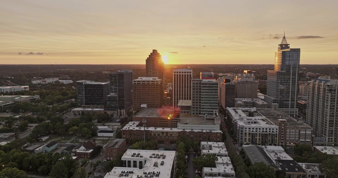 Raleigh, Carolina do Norte. Aéreo v72, sobrevoo baixo sobre Moore Square em direção ao horizonte do centro da cidade enquanto o sol se põe atrás da cidade. Filmado com Mavic 3 Pro Cine - 30 de setembro de 2023.