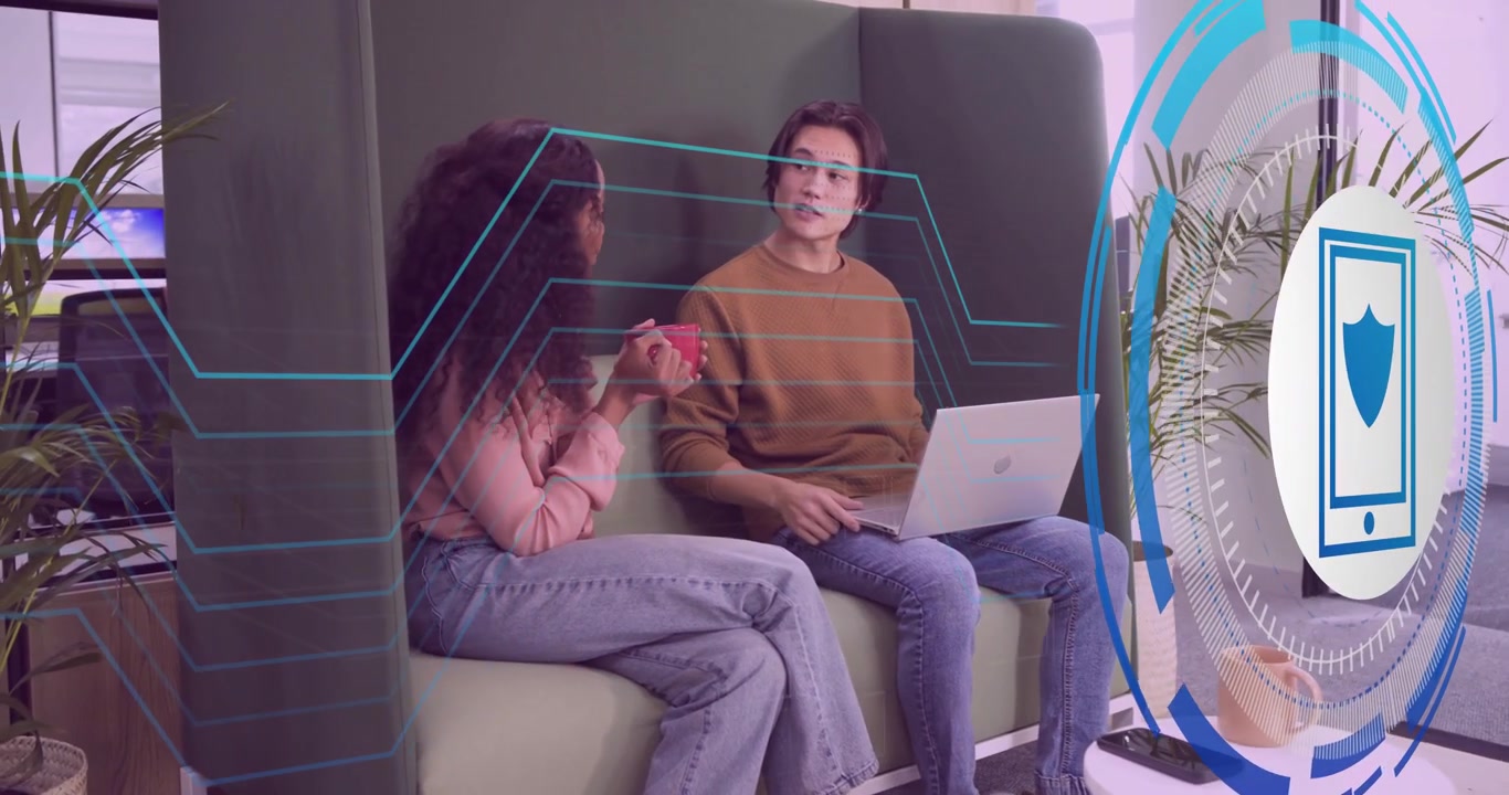 Due uomini nel settore tecnologico che digitano sul laptop sorseggiando da una tazza prima di attivare l'icona a scudo che mostra il flusso di rete.