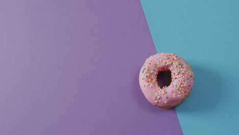 Video-Von-Donut-Mit-Zuckerguss-Auf-Violettem-Und-Blauem-Hintergrund