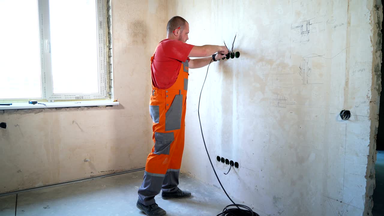 Electrician laying wiring cable lines inside of wall.