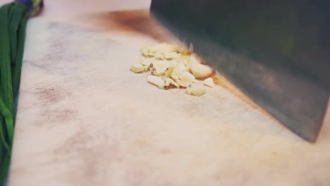 a chef slices garlic on chopping board close up