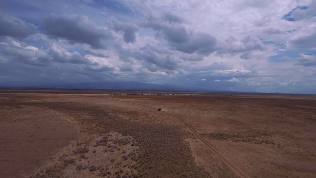 Drone shot of SUV Driving through African savannah. Rangers tracking Poachers. Tourists on safari