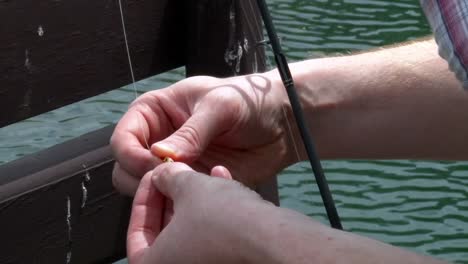 man putting bait on fish hook - close up