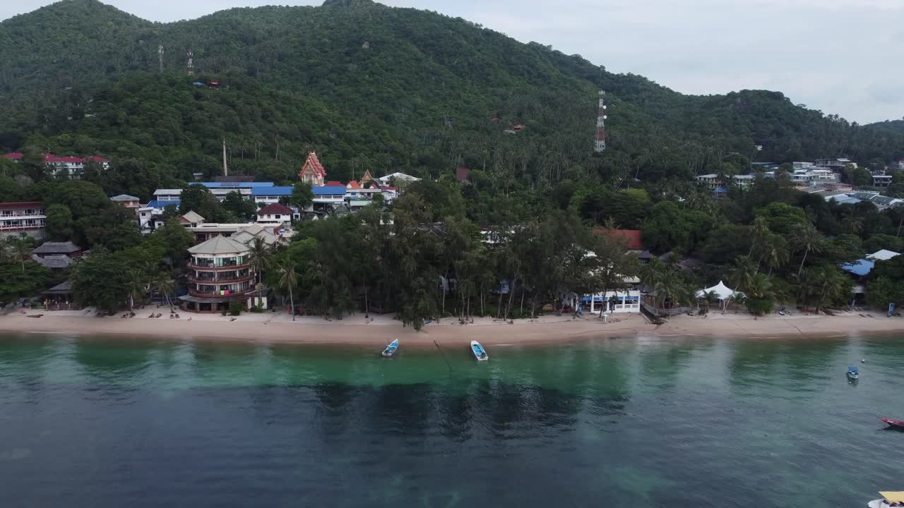 Toma aérea con dron de Koh Tao, Tailandia, en el sudeste asiático, con complejos turísticos y un pequeño pueblo de pescadores y buceadores sobre el agua azul y la jungla