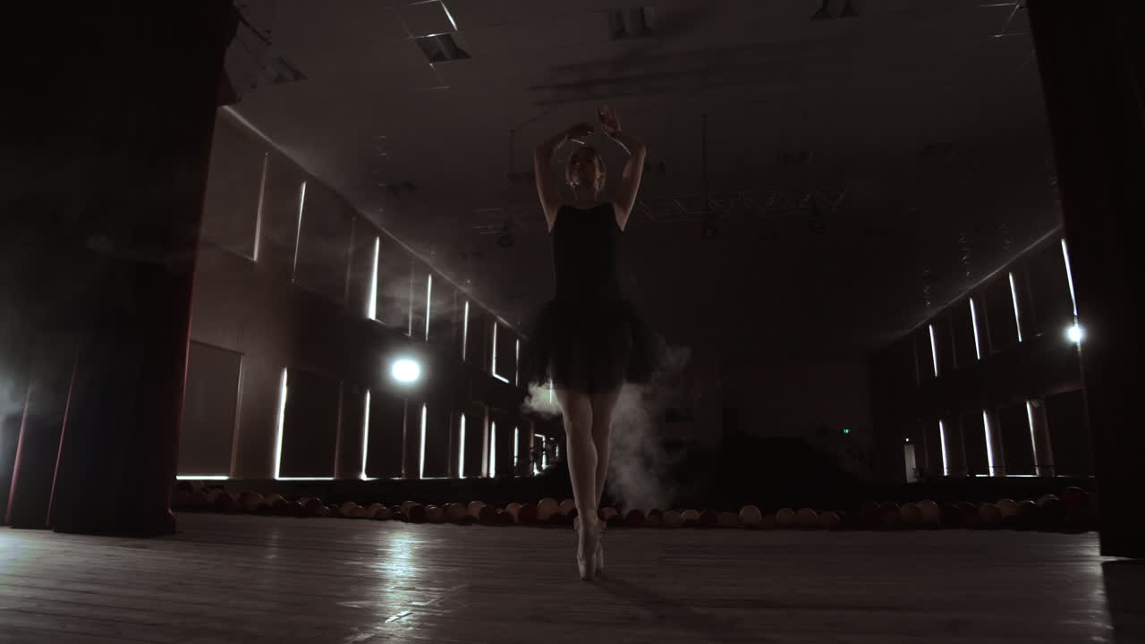 joven bailarina hermosa en el escenario de humo bailando ballet moderno. realiza movimientos suaves con las manos