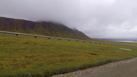 pov shot to the side, while driving on the dalton highway, of the trans-alaska pipeline system, on a dark, gloomy, fall day, in alaska, usa