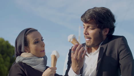 alegre pareja árabe comiendo helado al aire libre y hablando