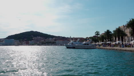 Barcos-Amarrados-En-El-Paseo-Marítimo-En-Split-Mientras-Un-Avión-Vuela-Al-Fondo.