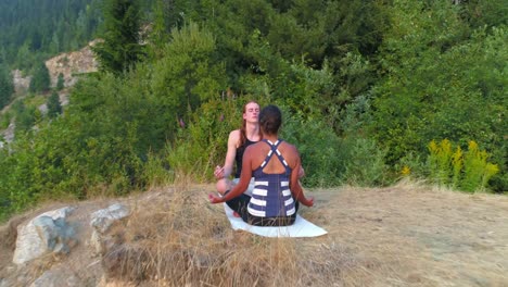 friends performing yoga on top of a mountain 4k