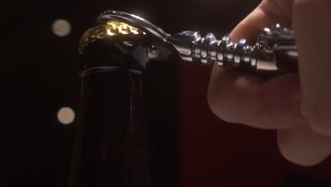 slow close-up: back lit beer bottle opened with chrome bottle opener