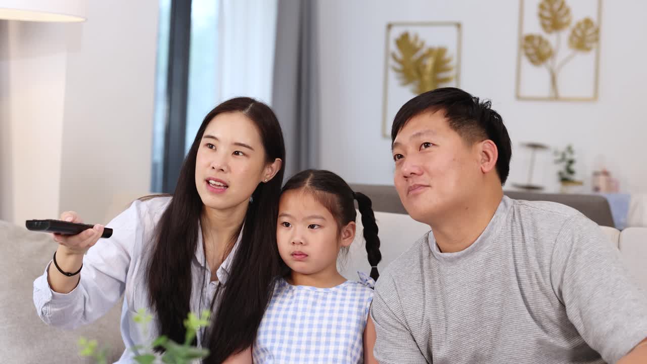 A family of three shares a joyful moment on the couch, with warm lighting and a cozy atmosphere