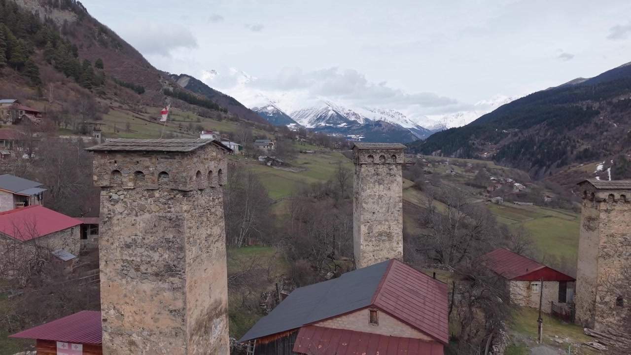 Voo de Drone Perto de uma Torre Svan Histórica Realizando um Pullback, Revelando os Edifícios Tradicionais de Mestia e a Espetacular Paisagem Montanhosa do Cáucaso em Svaneti, Geórgia