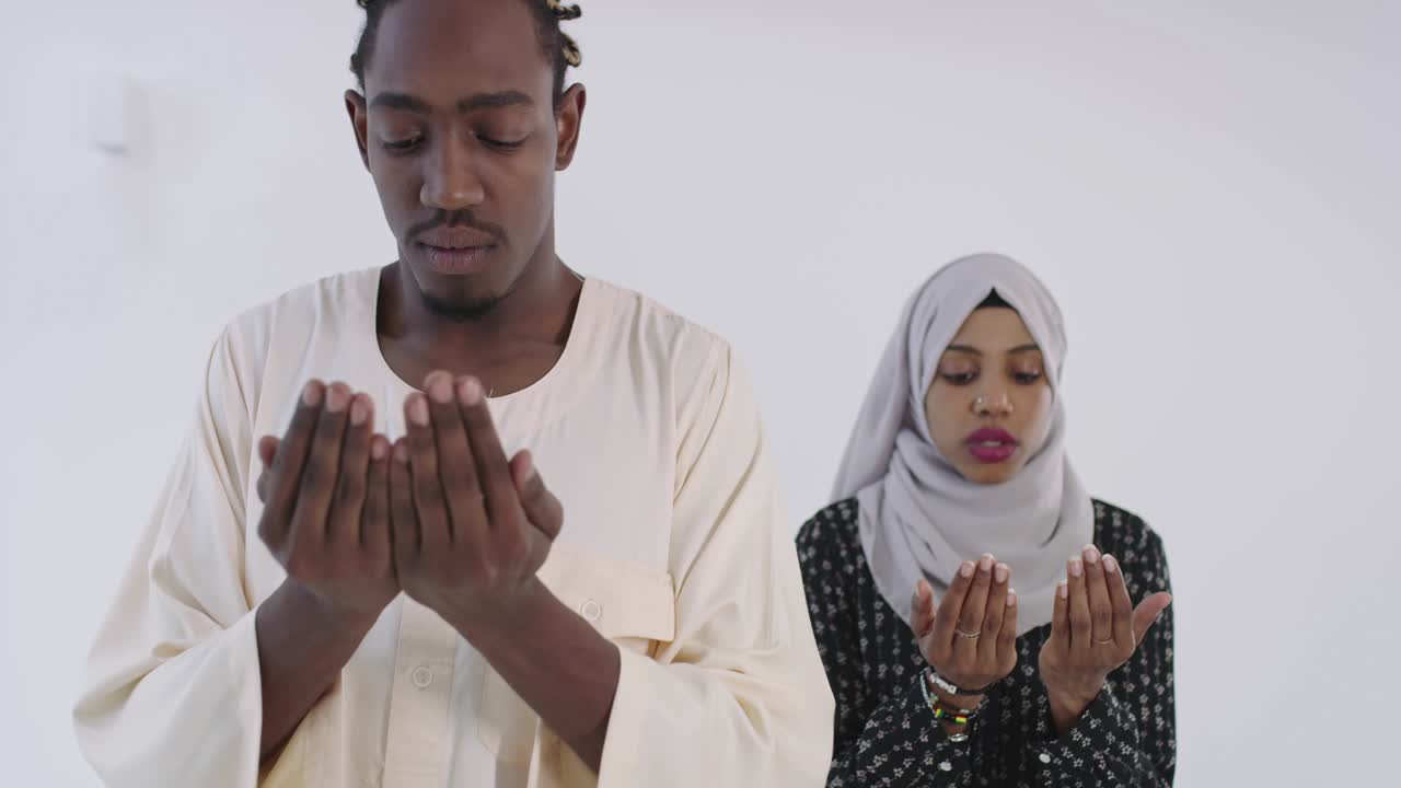 African black muslim couple at home in ramadan Making Traditional Fatiha Prayer To Allah God While Wearing A Traditional Sudan fashion clothes in studio