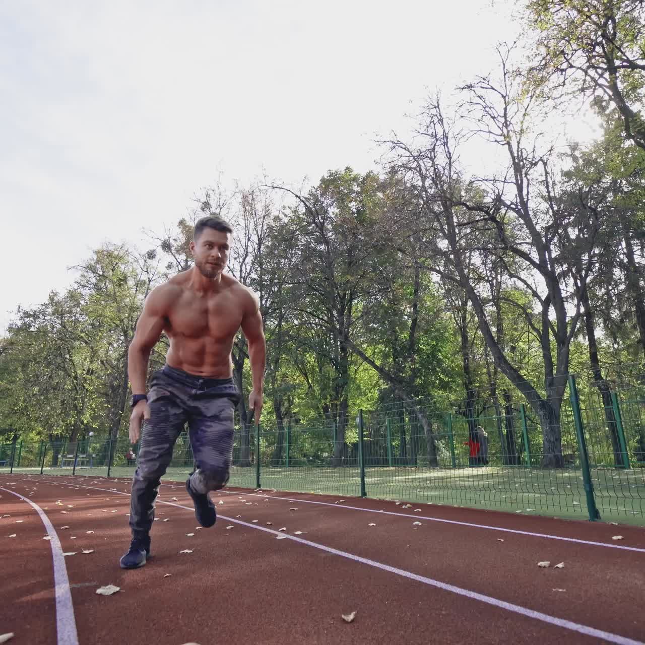 Handsome man training on the field stadium. Young muscular athlete runs on the sports track outdoors. Healthy lifestyle.