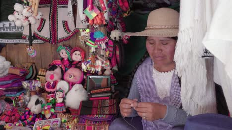 medium shot of traditional woman (cholita) weaving in the recoleta market, sucre