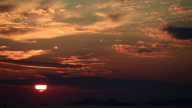Sunset creating a warm orange glow across the sky, with the sun dipping below the horizon