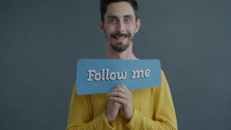 man holding a sign saying "follow me"