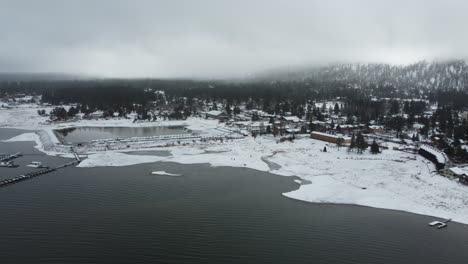 aerial view of big bear lake and village harbor on cold winter day, snow capped coast and marina, california usa