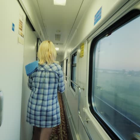 a woman with a towel is walking along the carriage of a passenger train 1