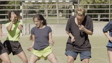 front view of cheerful female football players dancing on the field after victory