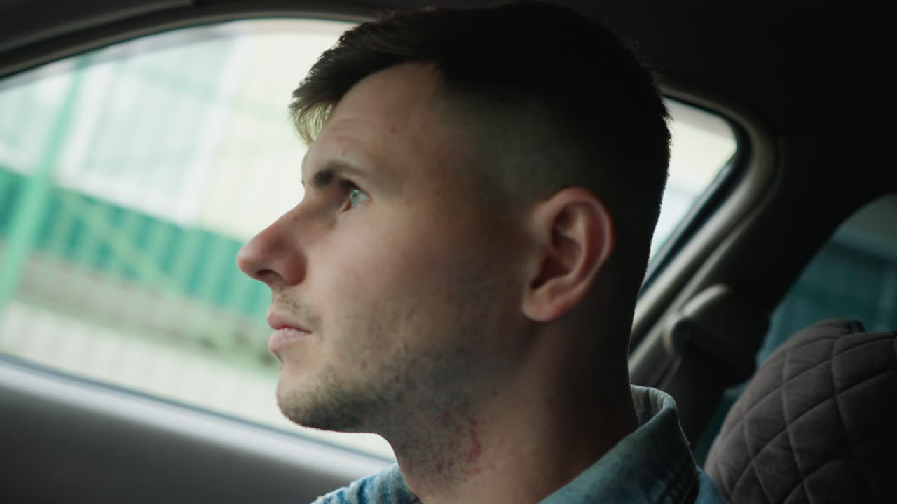 Jovem observa a cidade, passageiro do sexo masculino observa os edifícios modernos da cidade de seu veículo, jovem observa de perto as estruturas dinâmicas e movimentadas da cidade de vários pontos de vista